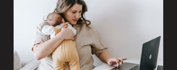 A multitasking woman attending to her child while working on a computer