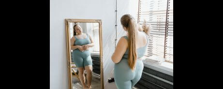 A lady affirming herself in the mirror, one of the examples of positive self-talk